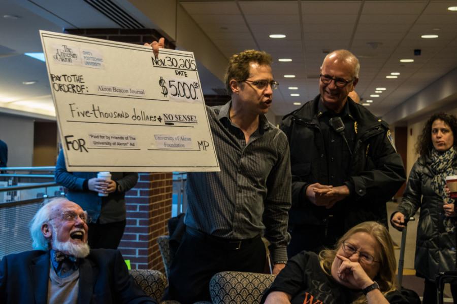 UA grad student Tom Guarino at Dec. 9's Board of Trustees protest, holding up a $5,000 check to parody the UA Foundation's payment of the Nov. 29 Akron Beacon Journal ad. 