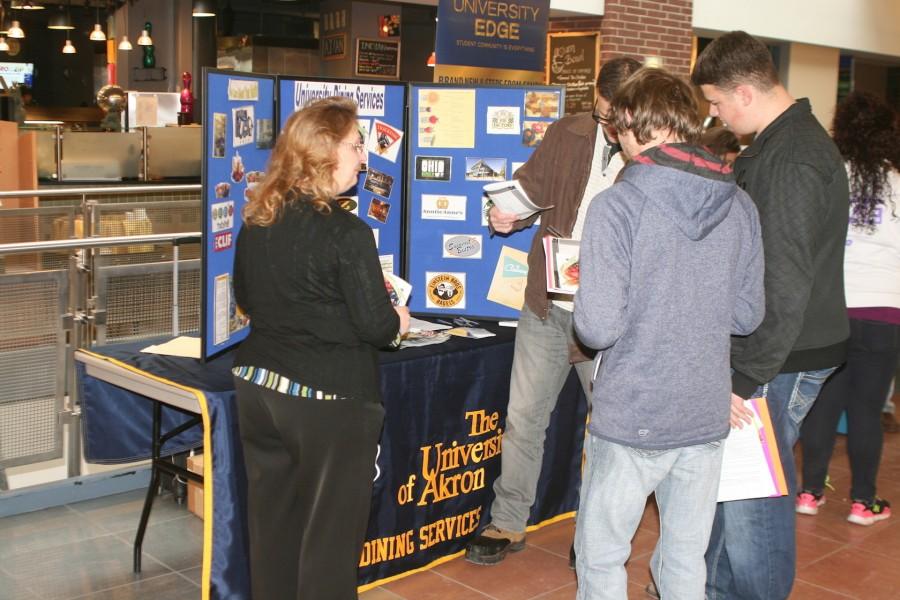 Three students receive dining plan information in front of the UA Dining Services table. 