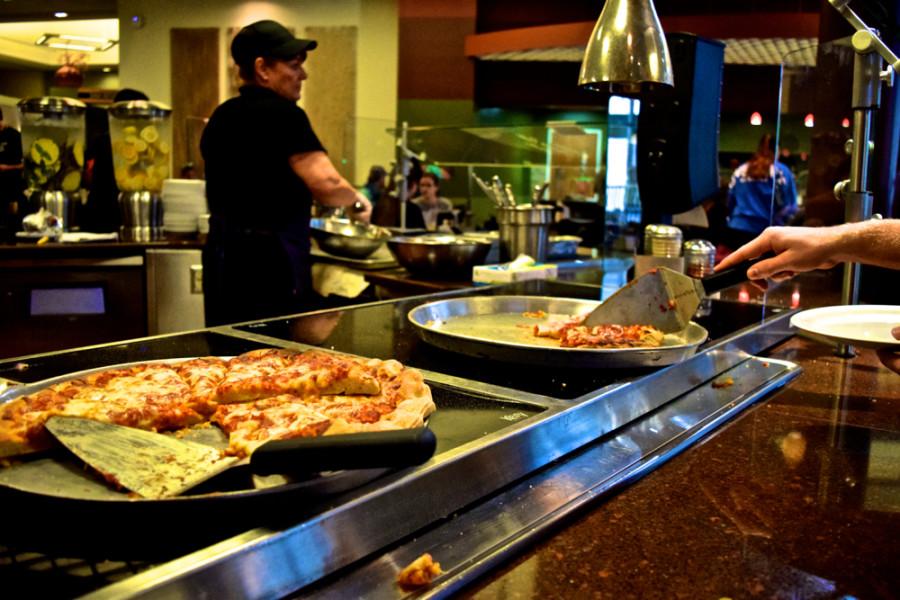 A student at Robs grabs a slice of pizza for dinner.