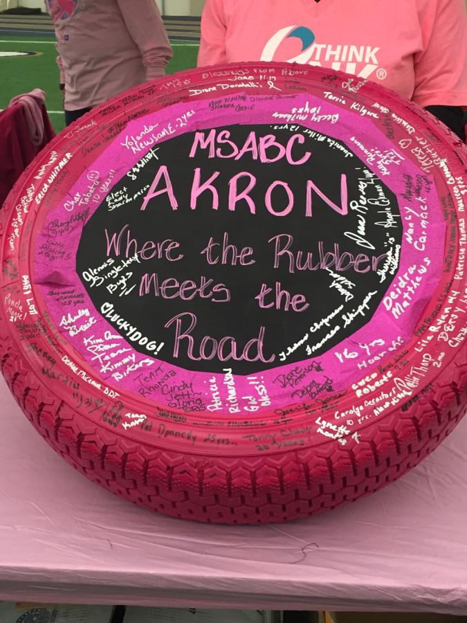 Survivors sign pink tire in honor of breast cancer awareness month. 