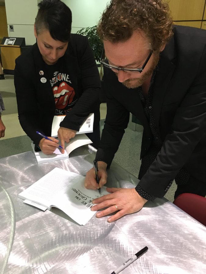 UA English professor David Giffels (right) signs a copy of 