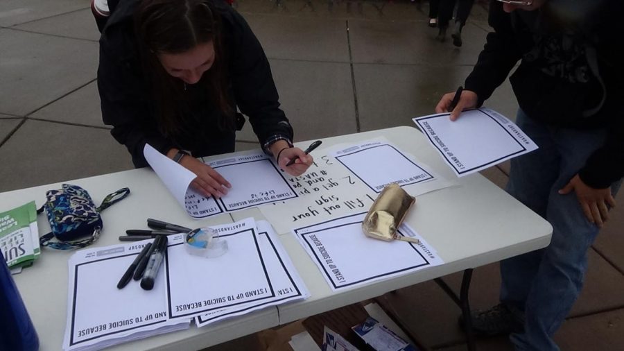 Students fill out “I stand up to suicide because” signs.
