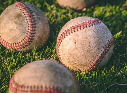 Baseballs sitting in grass 
